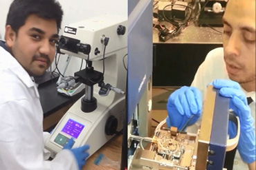 Two graduate students, one working at an advanced microscope, and the other at a circuit board